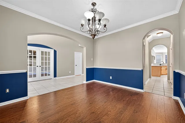 a view of a livingroom with a chandelier potted plants and wooden floor