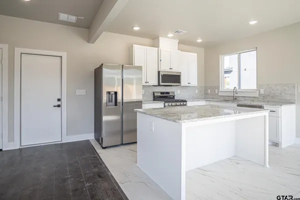 a kitchen with stainless steel appliances granite countertop a refrigerator and a stove top oven