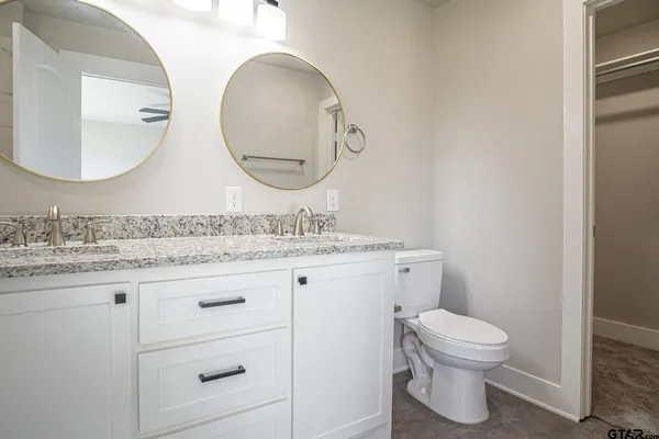 a bathroom with a granite countertop toilet sink mirror and vanity