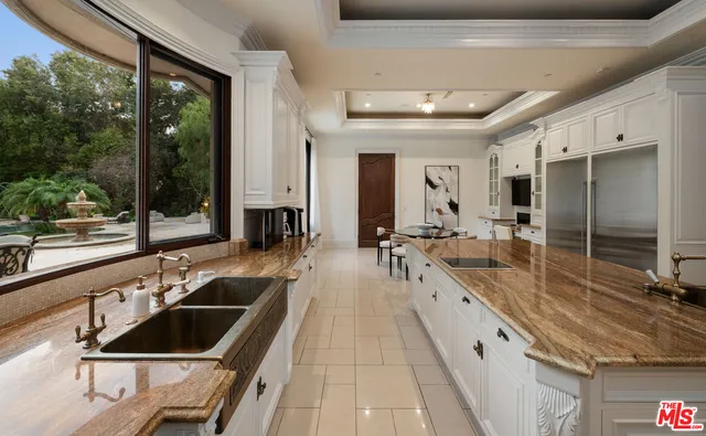 a large white kitchen with a large window and stainless steel appliances