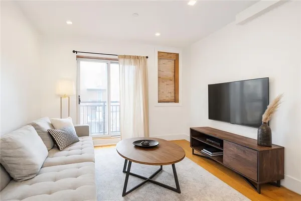 a living room with furniture a flat screen tv and a window