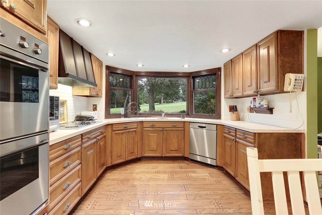 14811 Southeast 172nd Place Renton, WA 98058 - Photo 10 of 24 a kitchen with stainless steel appliances granite countertop a refrigerator a sink dishwasher a stove and white countertops with wooden floor
