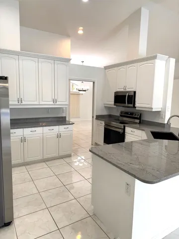 a kitchen with kitchen island granite countertop a sink a counter top space appliances and cabinets