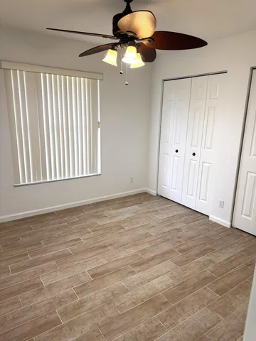 a view of an empty room with a window and chandelier fan