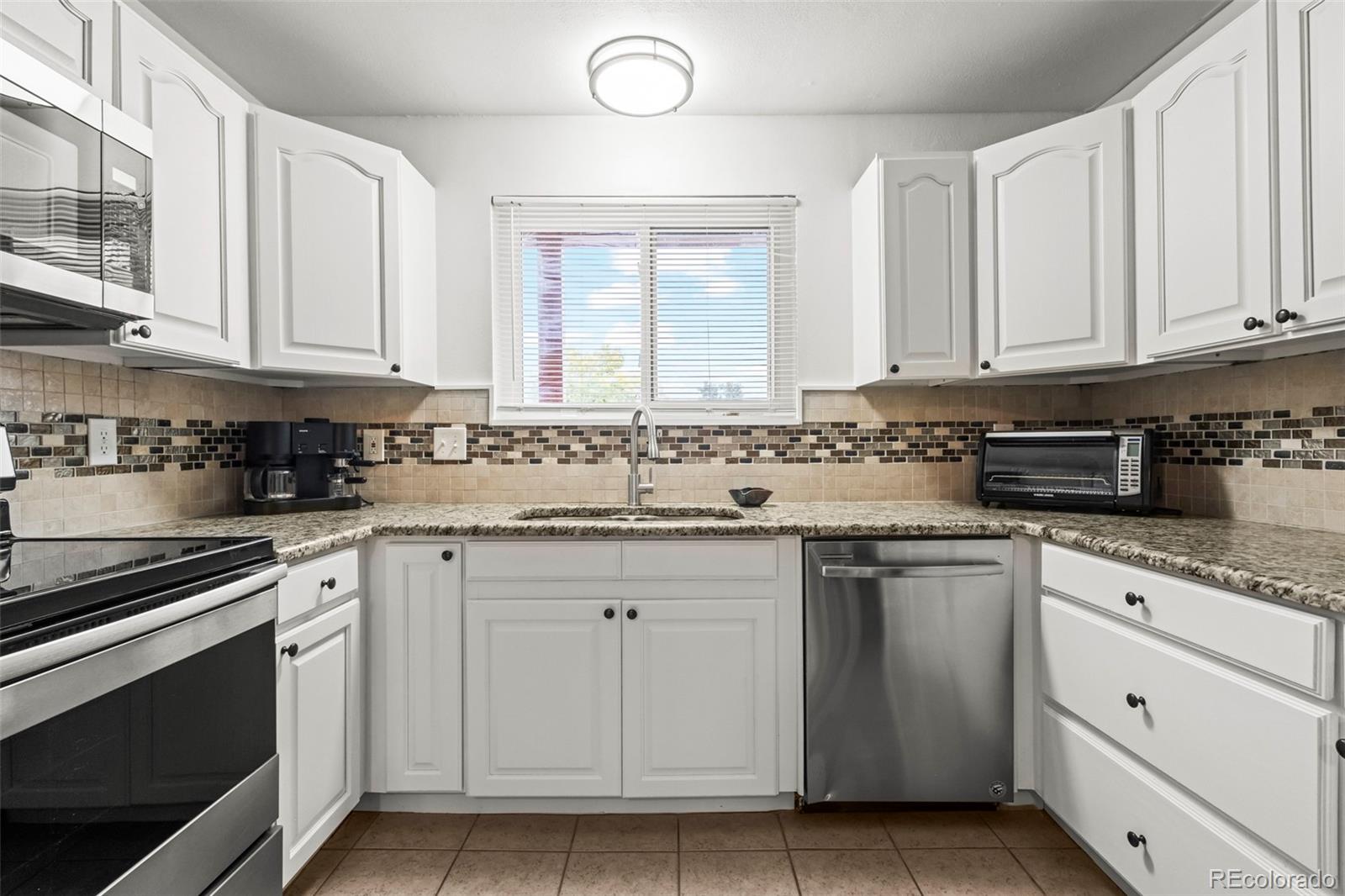 8450 Decatur Street, Unit 98 Westminster, CO 80031 - Photo 11 of 23 a kitchen with granite countertop white cabinets and white stainless steel appliances