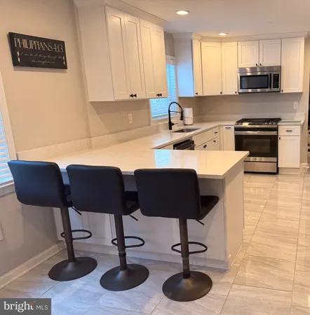 a view of kitchen with stainless steel appliances kitchen island granite countertop a stove a sink a table and chairs