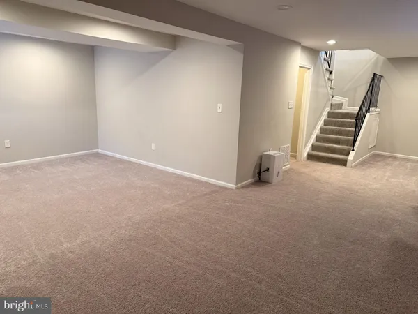 a view of an empty room with stairs and a window