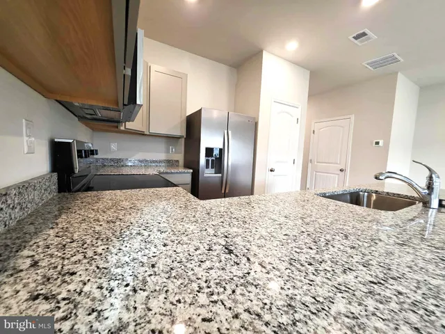 a kitchen with stainless steel appliances kitchen island granite countertop a refrigerator and a sink