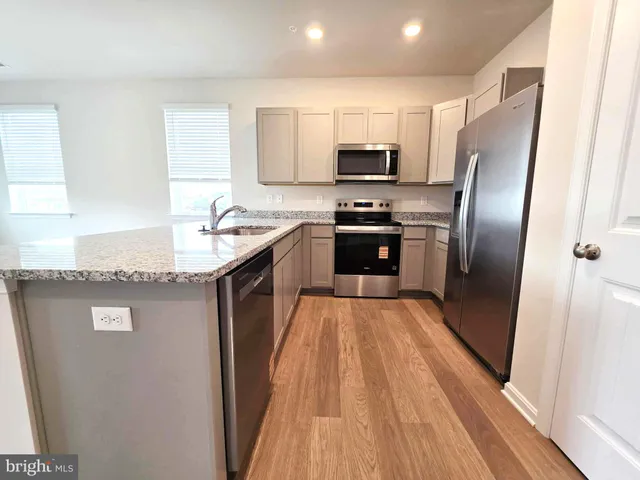 a kitchen with stainless steel appliances granite countertop a refrigerator a stove a sink and a microwave