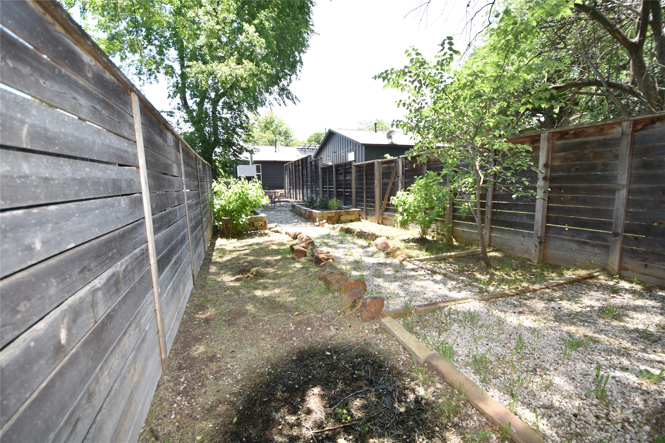 2012 Payne Avenue, Unit A Austin, TX 78757 - Photo 32 of 33 Fenced yard featuring a gravel pathway, raised garden beds, and mature trees