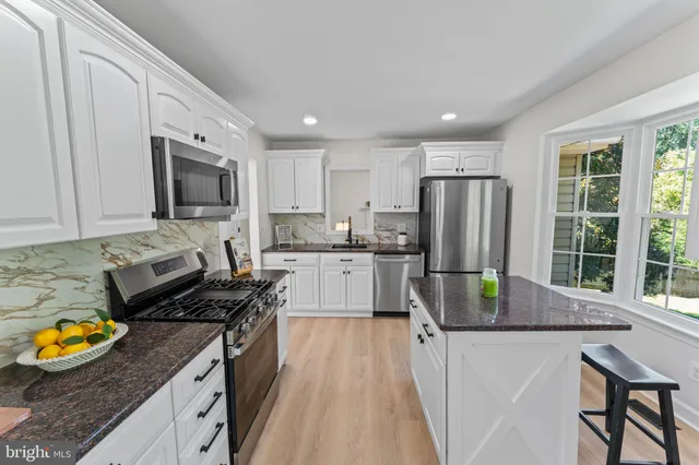 a kitchen with stainless steel appliances granite countertop sink stove top oven and cabinets