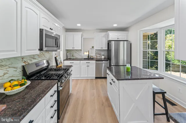 a kitchen with stainless steel appliances granite countertop a refrigerator and a window