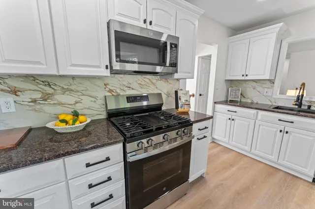 a kitchen with a stove a sink and a white cabinets