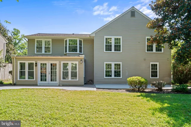 a front view of a house with garden and trees