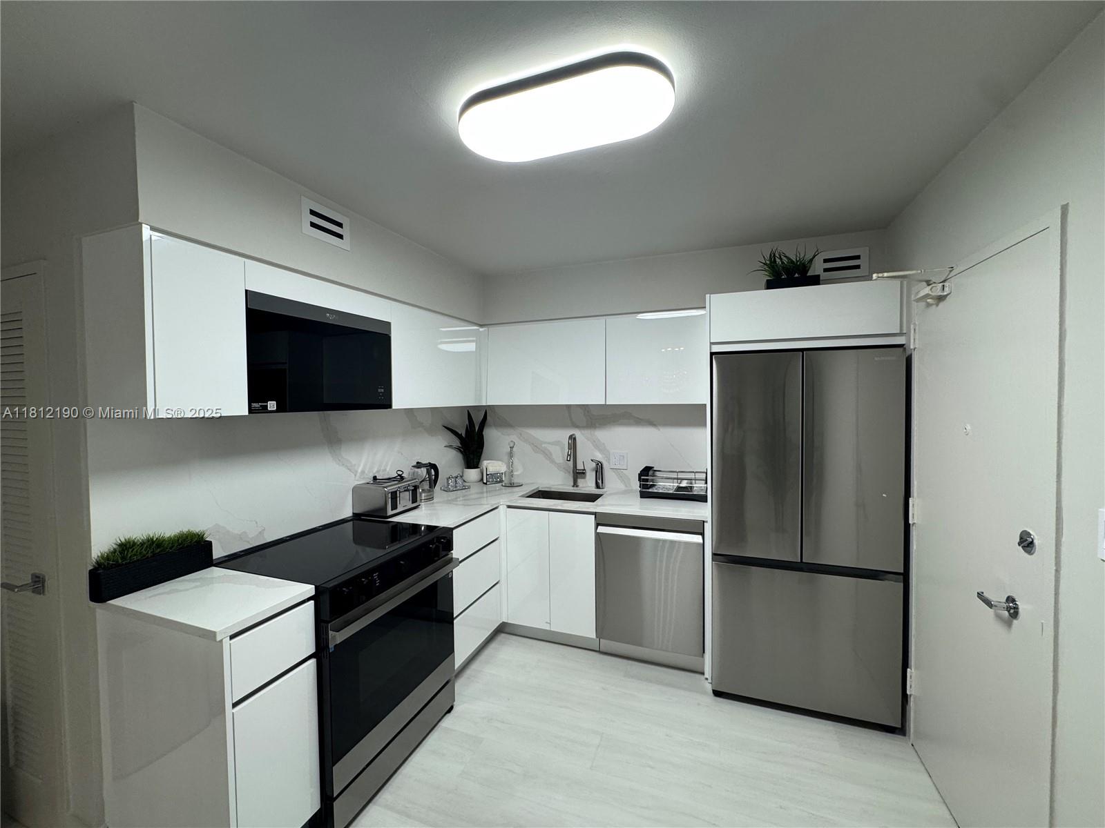 5151 Collins Avenue, Unit 726 Miami Beach, FL 33140 - Photo 12 of 32 a kitchen with a refrigerator sink and stove top oven