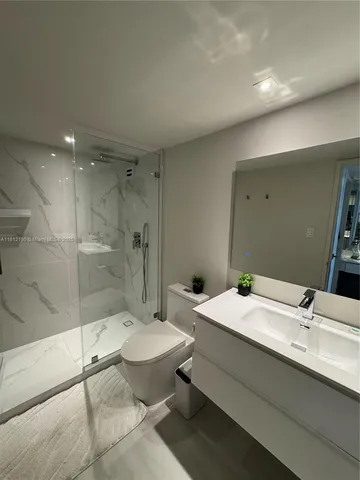 a bathroom with a granite countertop sink mirror toilet and shower