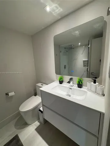 a bathroom with a granite countertop sink mirror a toilet and a mirror