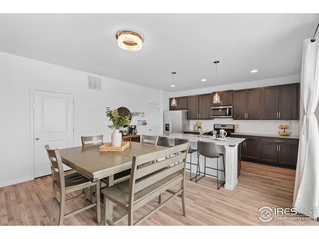 a living room with stainless steel appliances kitchen island granite countertop a table chairs and a refrigerator