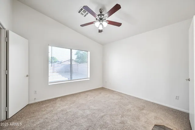 an empty room with windows and ceiling fan