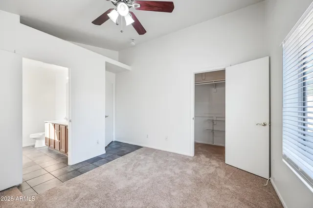 an empty room with a ceiling fan and carpet