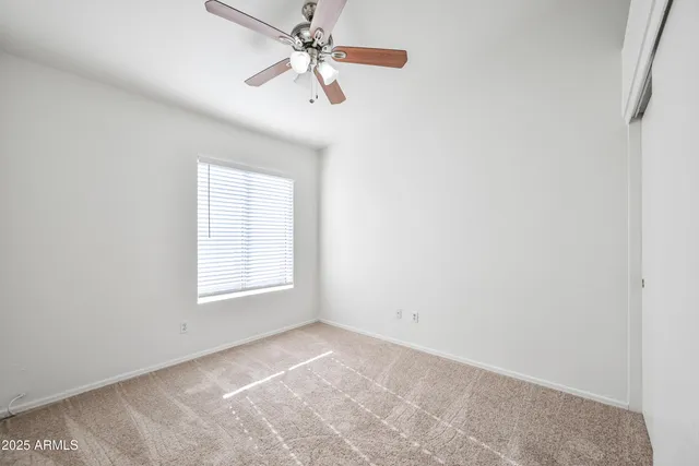 an empty room with windows and fan