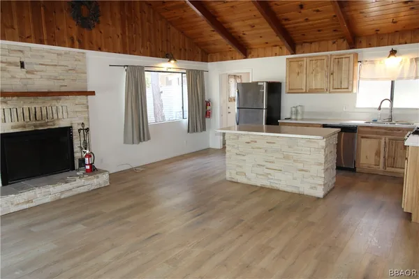 a kitchen with stainless steel appliances granite countertop a stove top oven a sink dishwasher and a fireplace with wooden floor