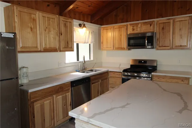 a kitchen with stainless steel appliances a sink a stove a microwave a sink and cabinets