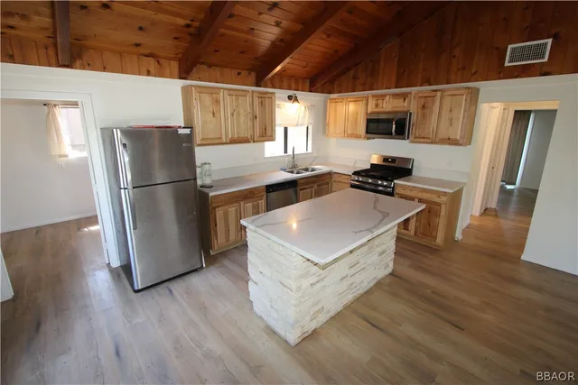 a kitchen with a refrigerator a stove top oven a counter space and wooden floor