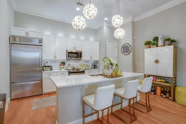 a kitchen with stainless steel appliances granite countertop a stove top oven a refrigerator a sink dishwasher a dining table and chairs with wooden floor