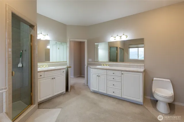 a bathroom with a toilet a double vanity sink and a mirror