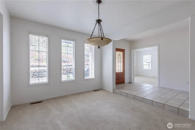 a view of an empty room with window and chandelier fan
