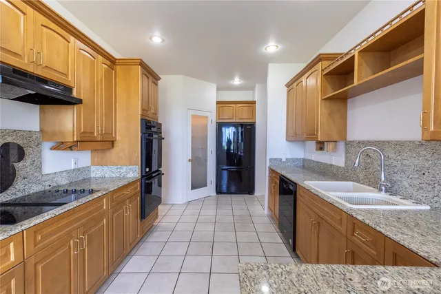 a large kitchen with stainless steel appliances granite countertop a sink and cabinets