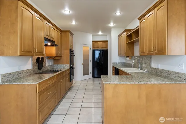 a large kitchen with granite countertop a sink a stove top oven and cabinets