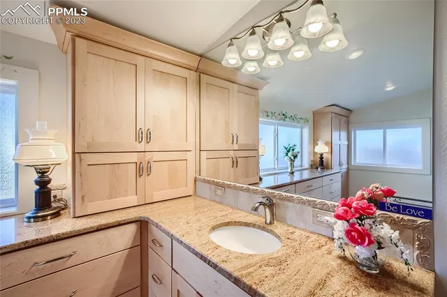 a bathroom with a granite countertop shower a sink and cabinets