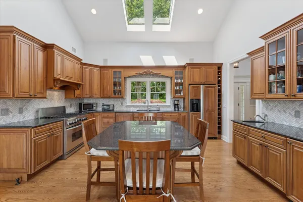 a kitchen with stainless steel appliances granite countertop a stove a sink dishwasher and a refrigerator with wooden cabinets