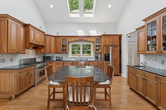 a kitchen with stainless steel appliances granite countertop a stove a sink dishwasher and a refrigerator with wooden cabinets