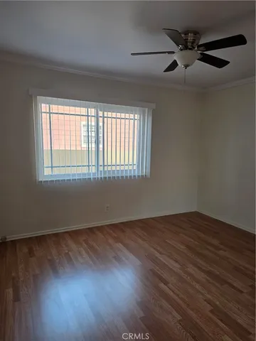 an empty room with wooden floor fan and windows