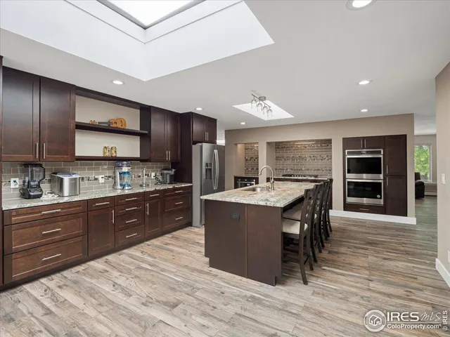 a kitchen with stainless steel appliances kitchen island granite countertop a stove refrigerator and cabinets