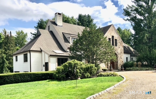 a view of a white house next to a yard with trees