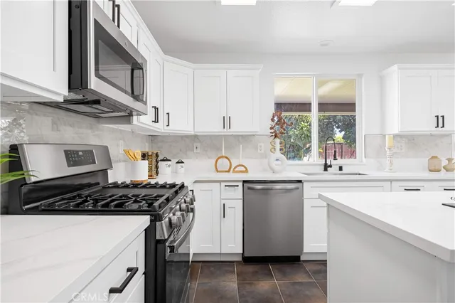 a kitchen with stainless steel appliances a stove a sink a stove and white cabinets