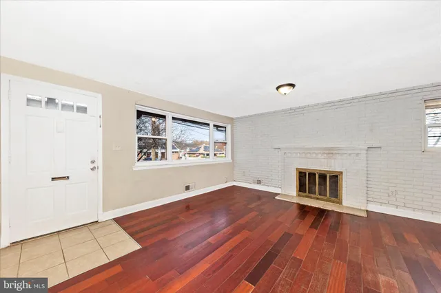 an empty room with wooden floor fireplace and windows