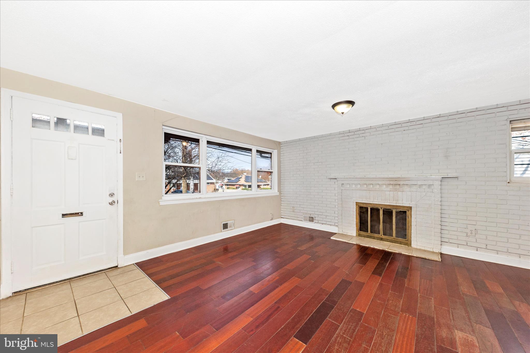 8109 Riggs Road Hyattsville, MD 20783 - Photo 7 of 54 an empty room with wooden floor fireplace and windows
