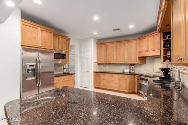 a kitchen with stainless steel appliances granite countertop a refrigerator a stove top oven a sink and dishwasher