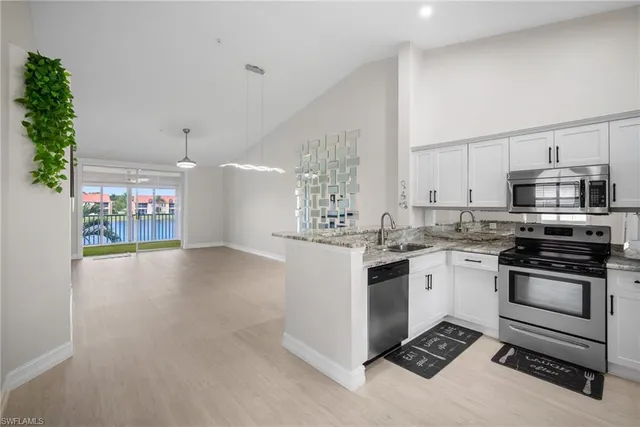 a kitchen with stainless steel appliances a sink a stove a refrigerator cabinets and a window