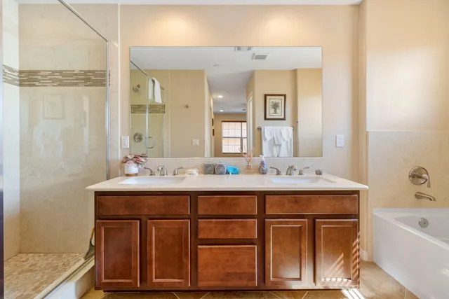 a bathroom with a sink double vanity granite tub shower and a mirror