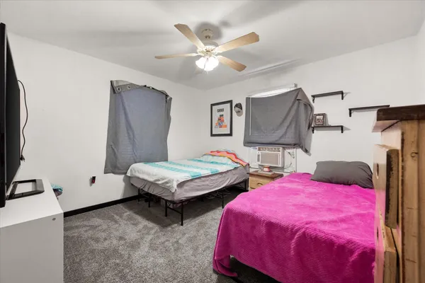a spacious bedroom with two bed and a flat tv screen on dresser