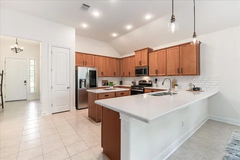 a large kitchen with a large counter top a stove a sink a microwave and a refrigerator