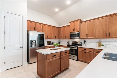 a kitchen with stainless steel appliances granite countertop a refrigerator oven a sink dishwasher and white cabinets with wooden floor