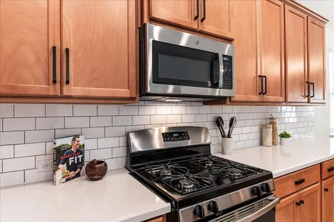 a kitchen with stainless steel appliances granite countertop a sink stove refrigerator and cabinets