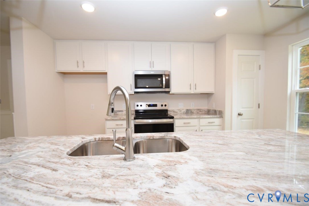 375 Amick Road Louisa, VA 23093 - Photo 10 of 25 a kitchen with granite countertop a sink and a stove top oven